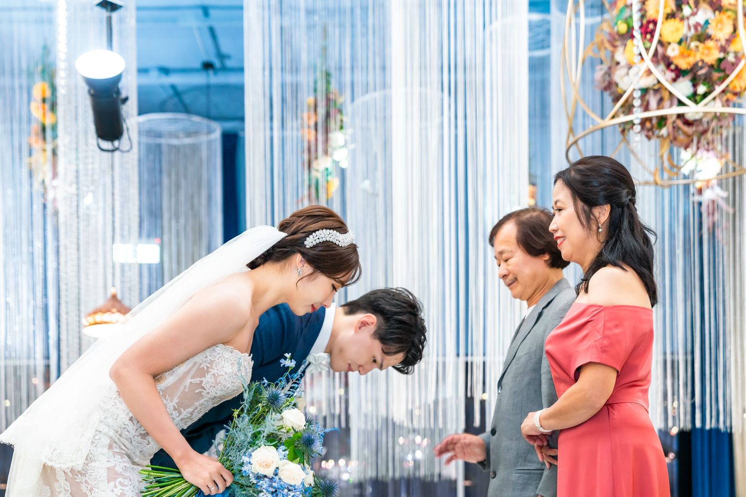 Wedding ceremony guests gathered under sparkling blue and silver decorative strings at an elegant indoor celebration.