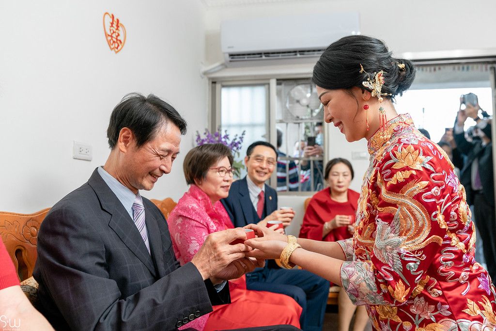Tea ceremony participants exchange cups during traditional Chinese wedding customs.