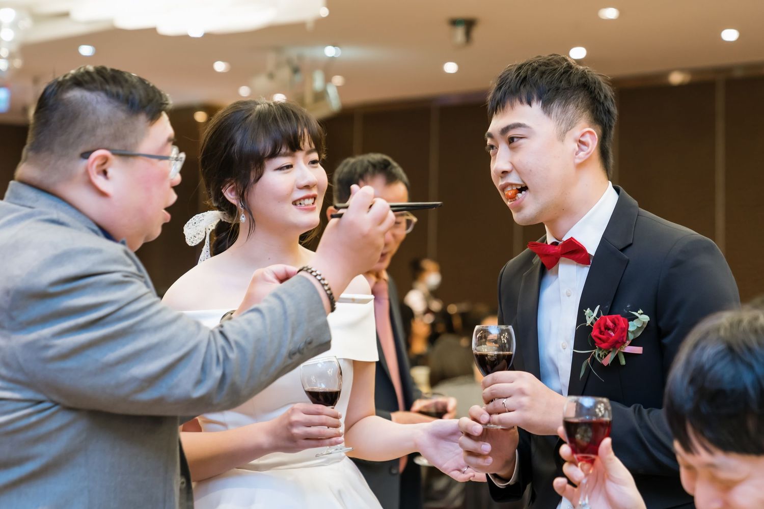 Wedding reception scene with guests toasting and sharing drinks with the couple.