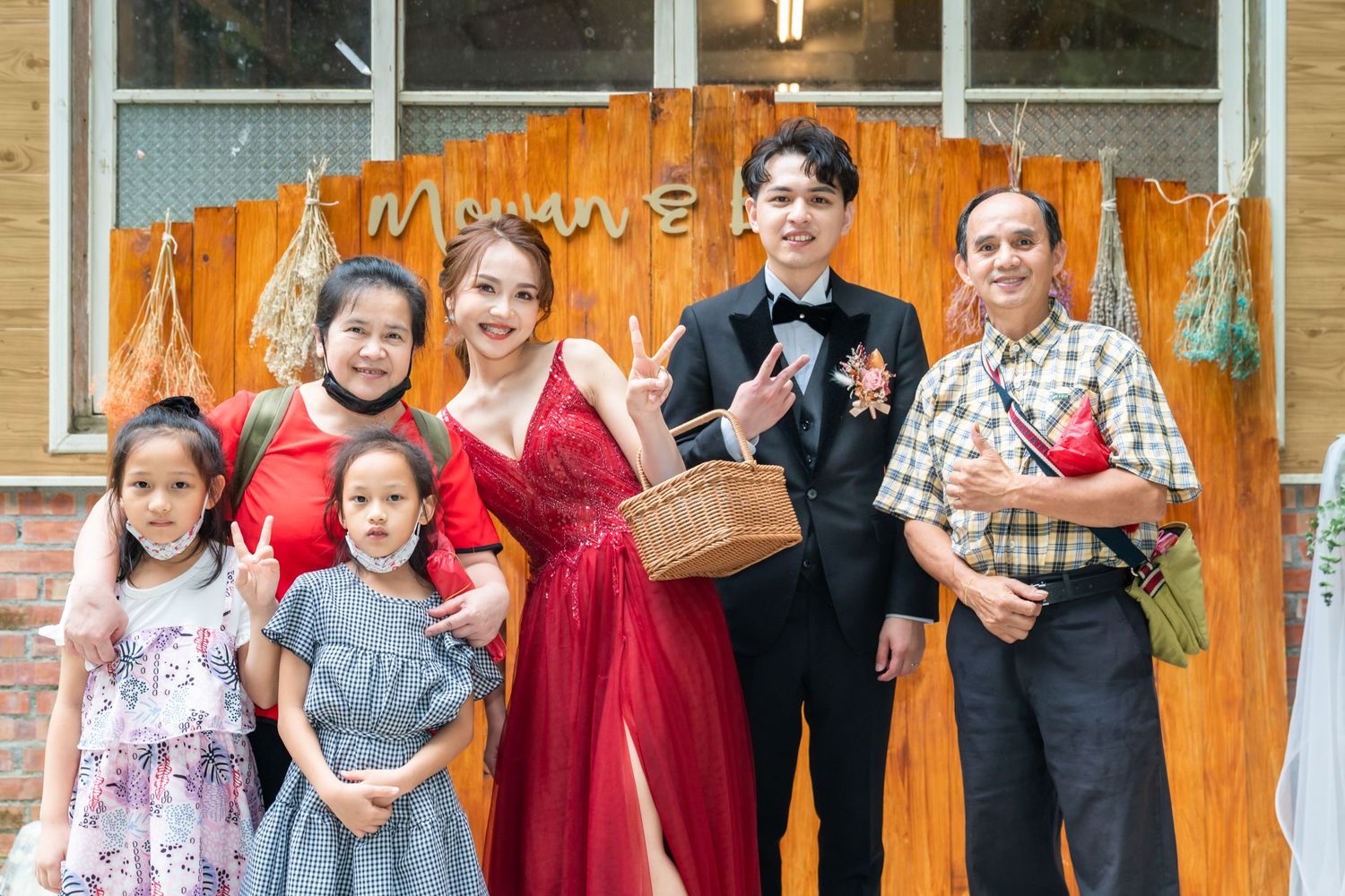 A group photo in front of an orange wall with formal and casual dressed individuals.
