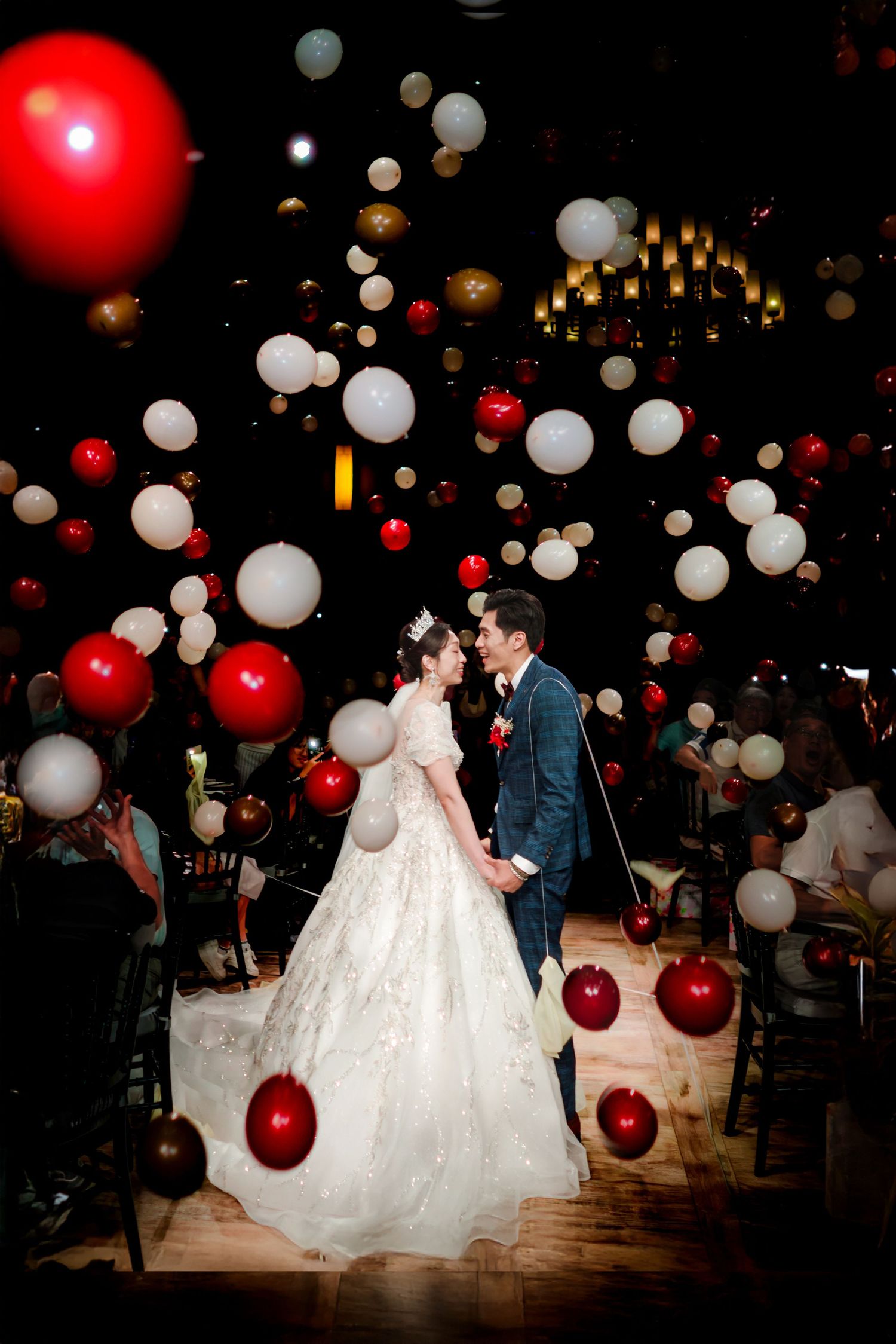 A romantic wedding celebration scene with white and red balloons creating a magical atmosphere in a dark venue.