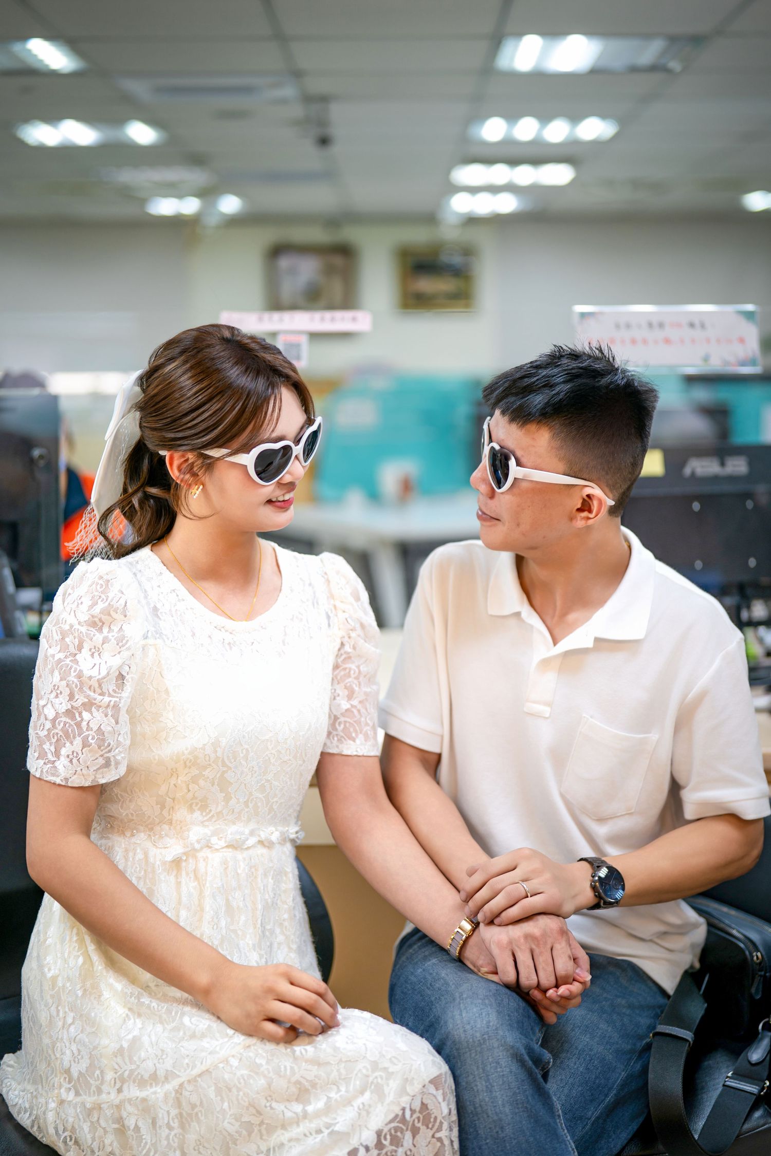 A couple in matching white outfits and sunglasses sit together in a series of casual poses.