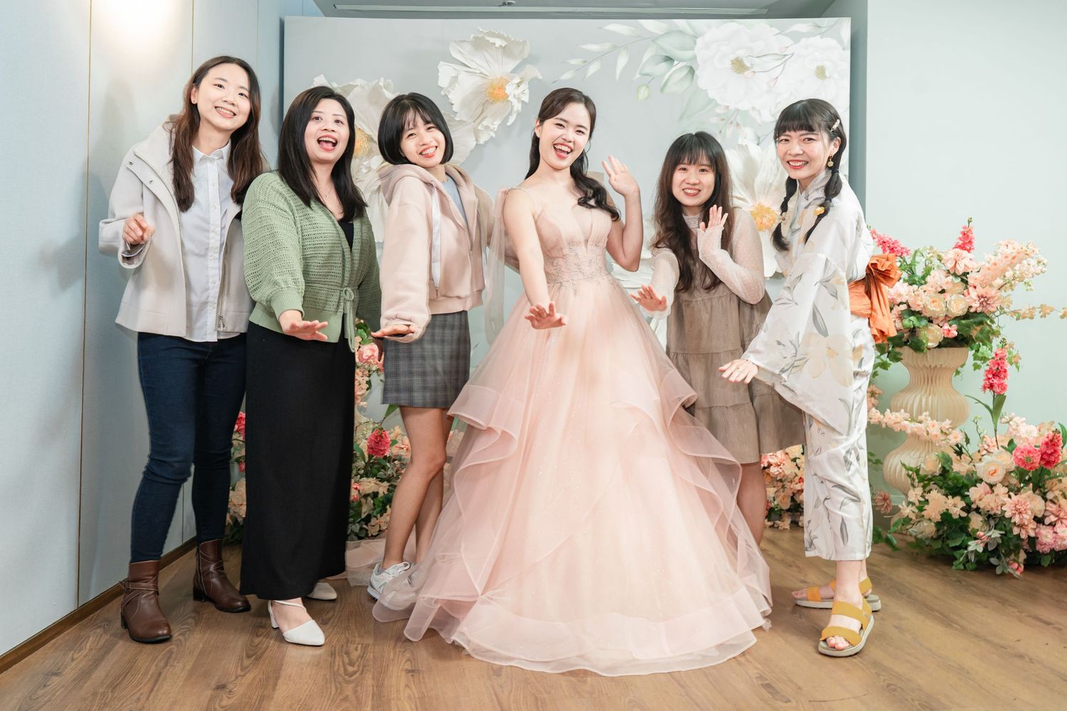 A group of people pose together in formal attire at a special celebration event with floral decorations.