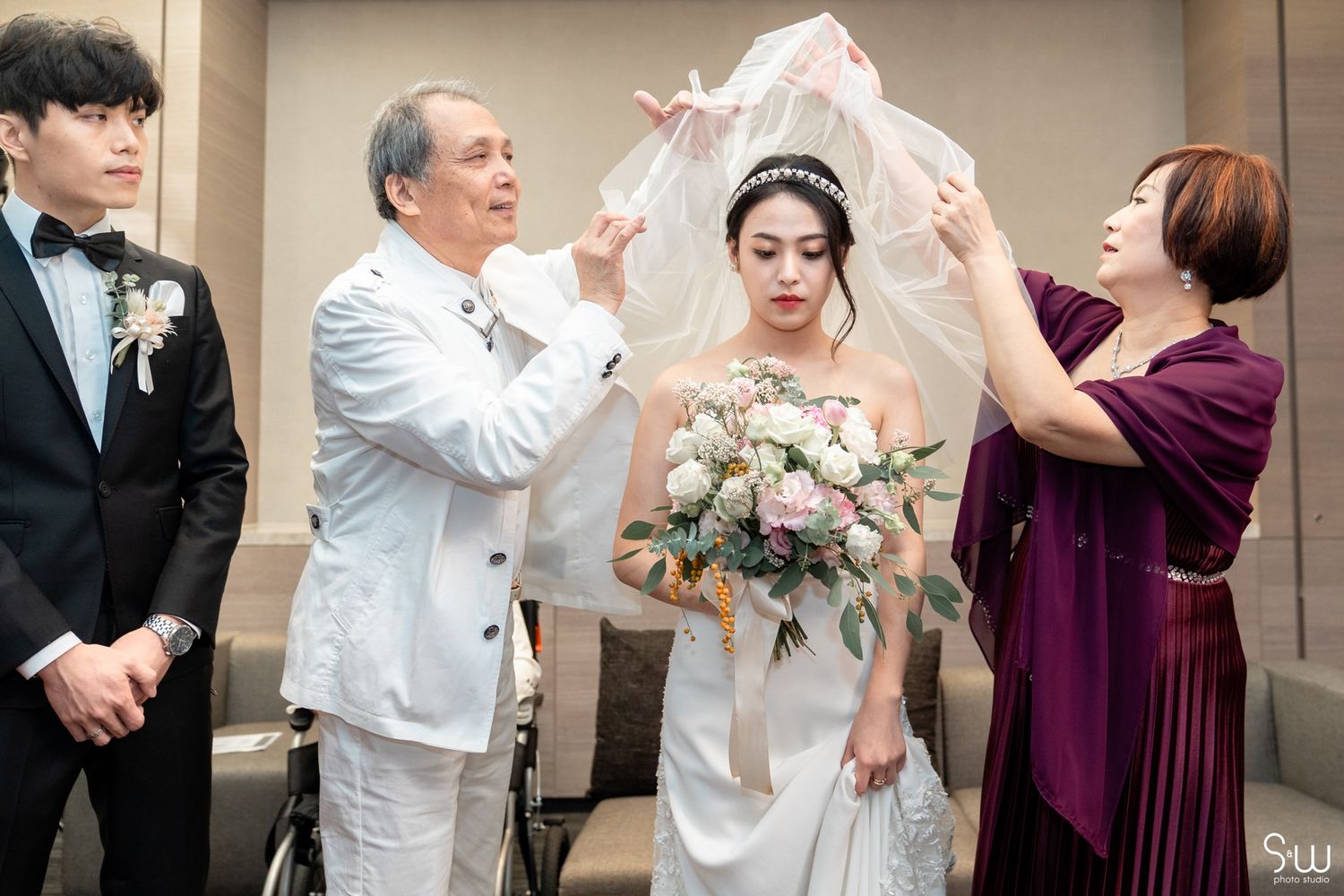 Wedding preparation scene with participants adjusting bride's veil.