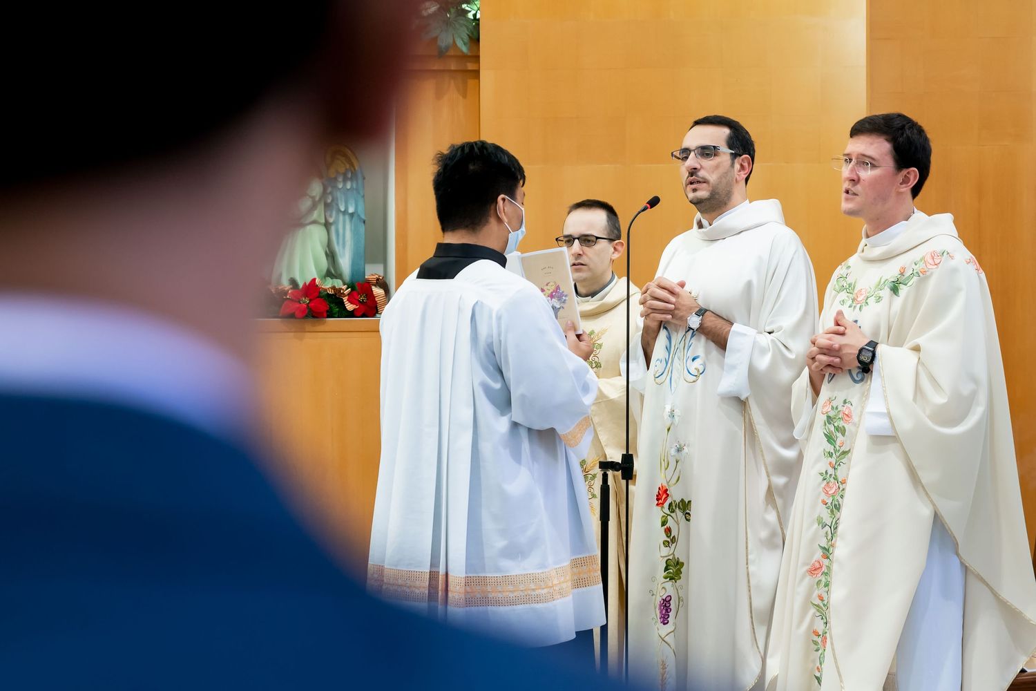 Priests in white robes gathered at church altar during ceremony.
