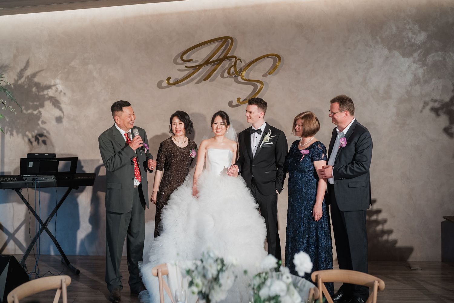 Wedding party in formal attire shares joyful moment together in elegant neutral-toned venue.