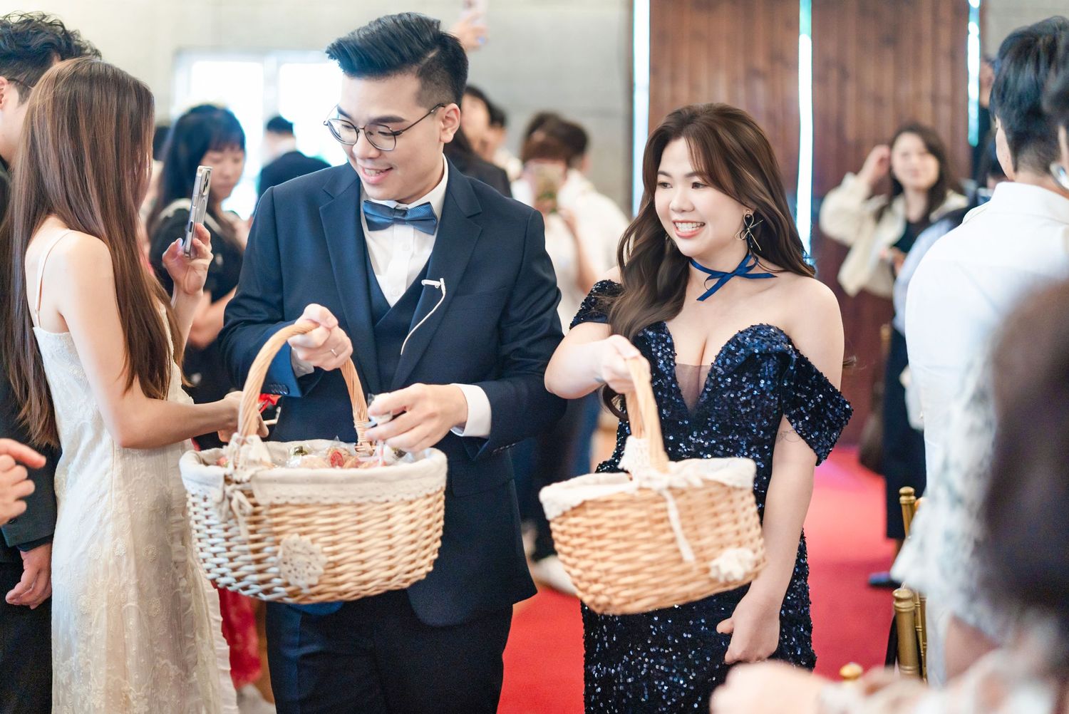 Elegant guests in formal attire holding wicker baskets at a social event gathering.