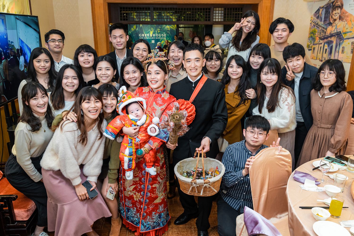 A festive group gathering for a celebration with people wearing traditional Chinese dress and modern attire.