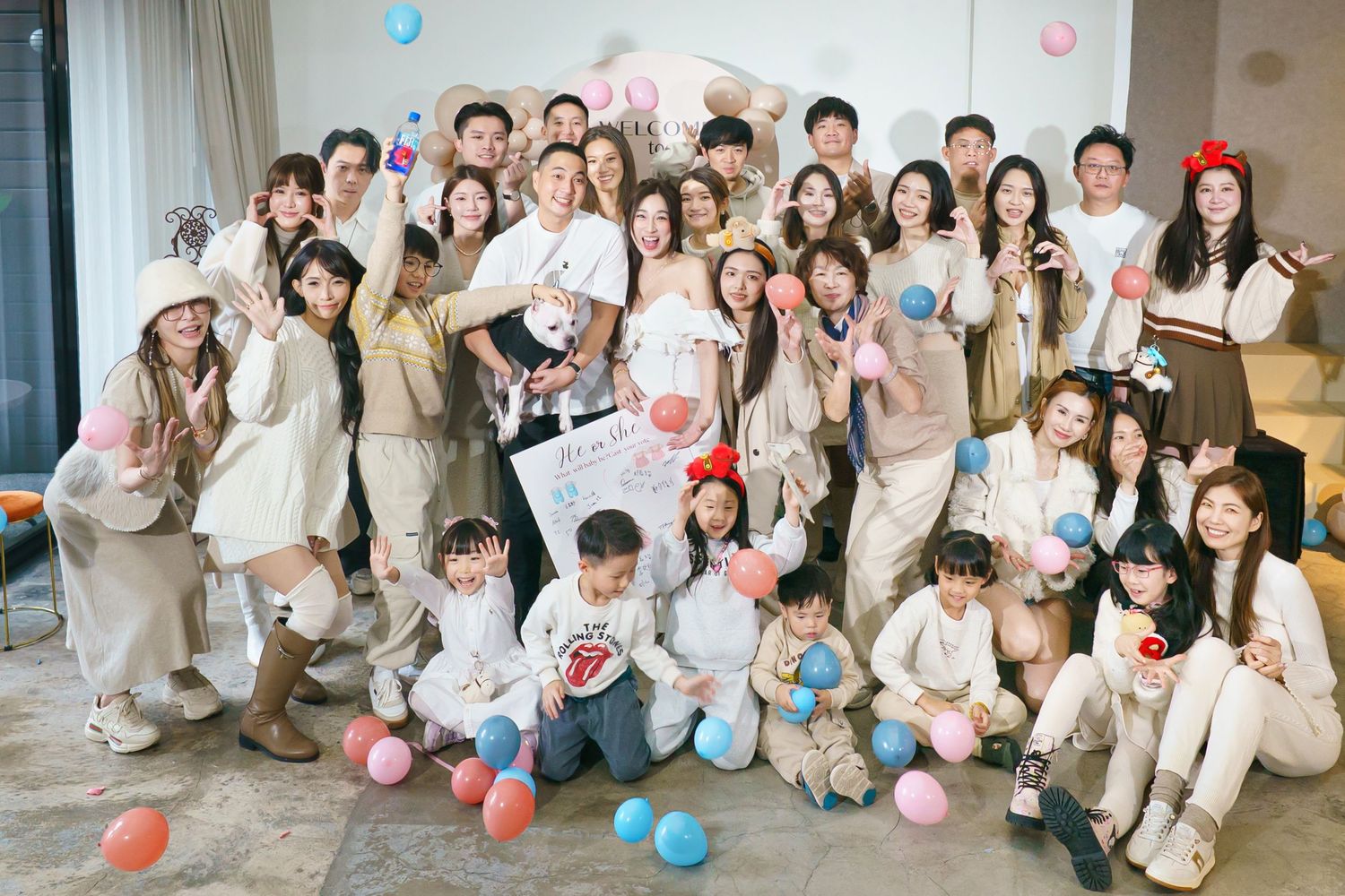 A group of people in white outfits pose with colorful balloons during a celebratory gathering.