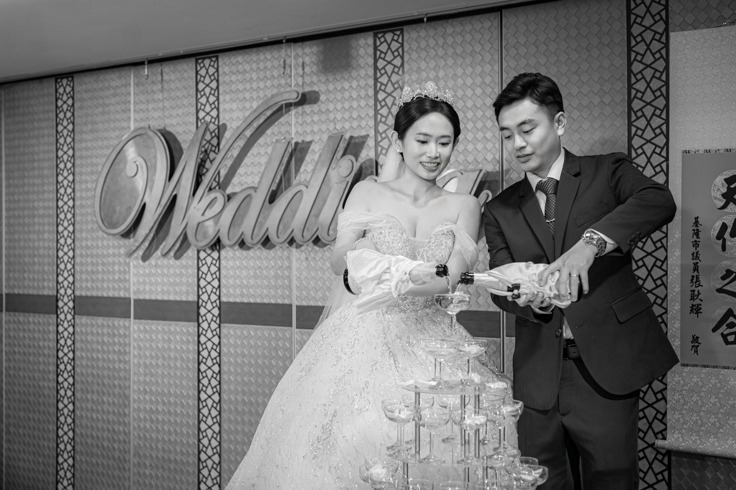 A bride and groom pour champagne into a tower of glasses at their vintage wedding reception.