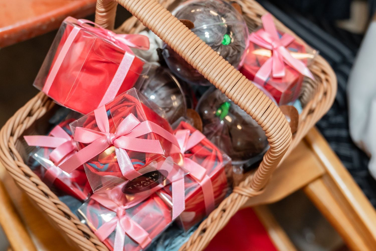 Festive gift basket filled with pink wrapped presents and decorative bows.