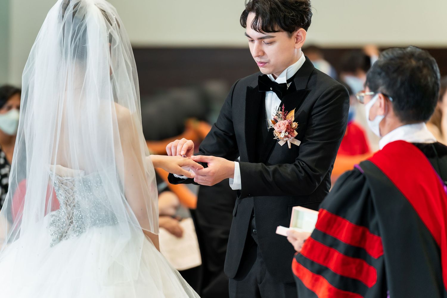 Wedding ring exchange ceremony at decorated altar with officiant present.