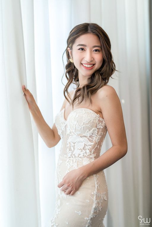 Bridal portrait showcasing delicate lace wedding gown against white curtain backdrop.