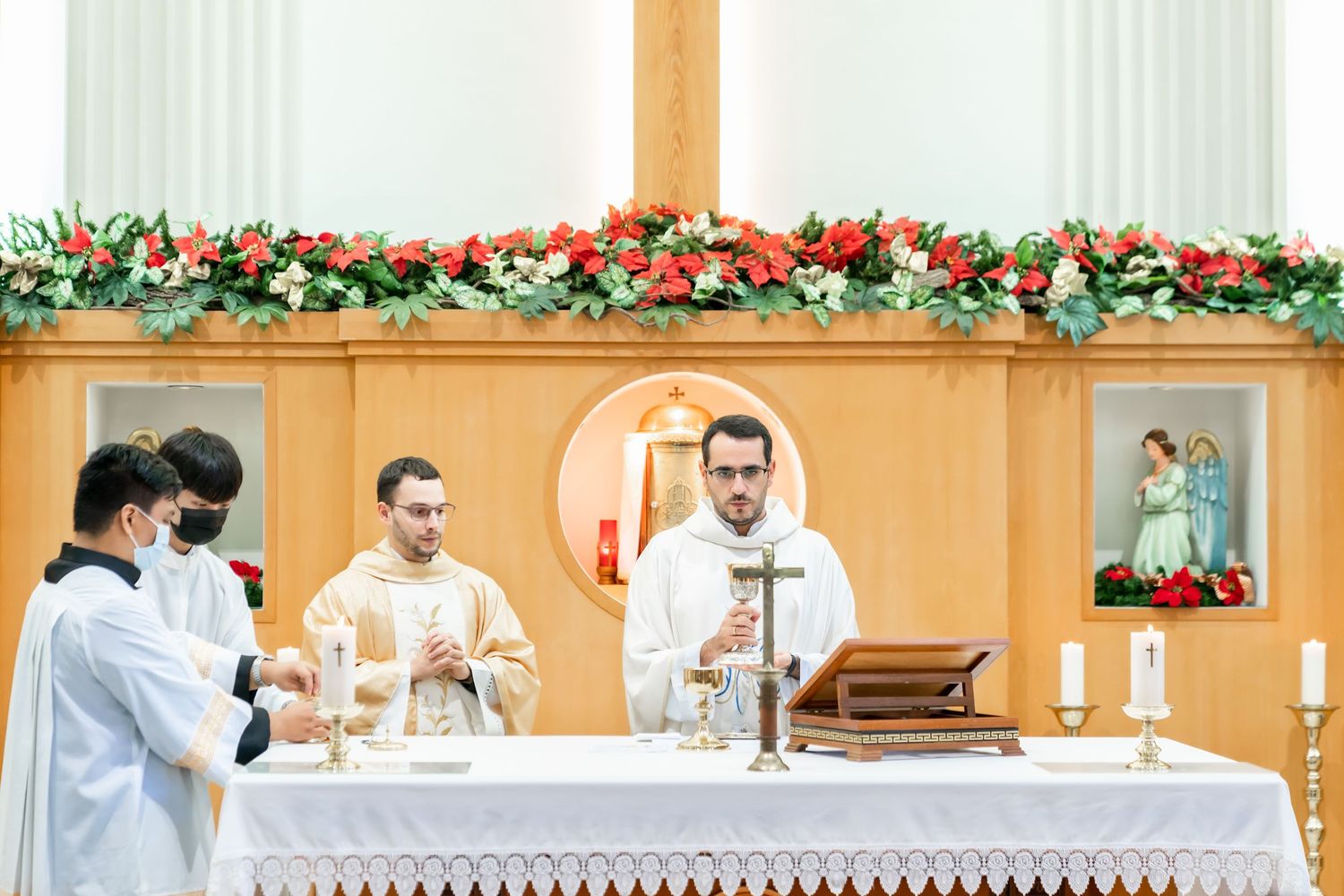 Three priests performing ceremonial duties at a decorated church altar.