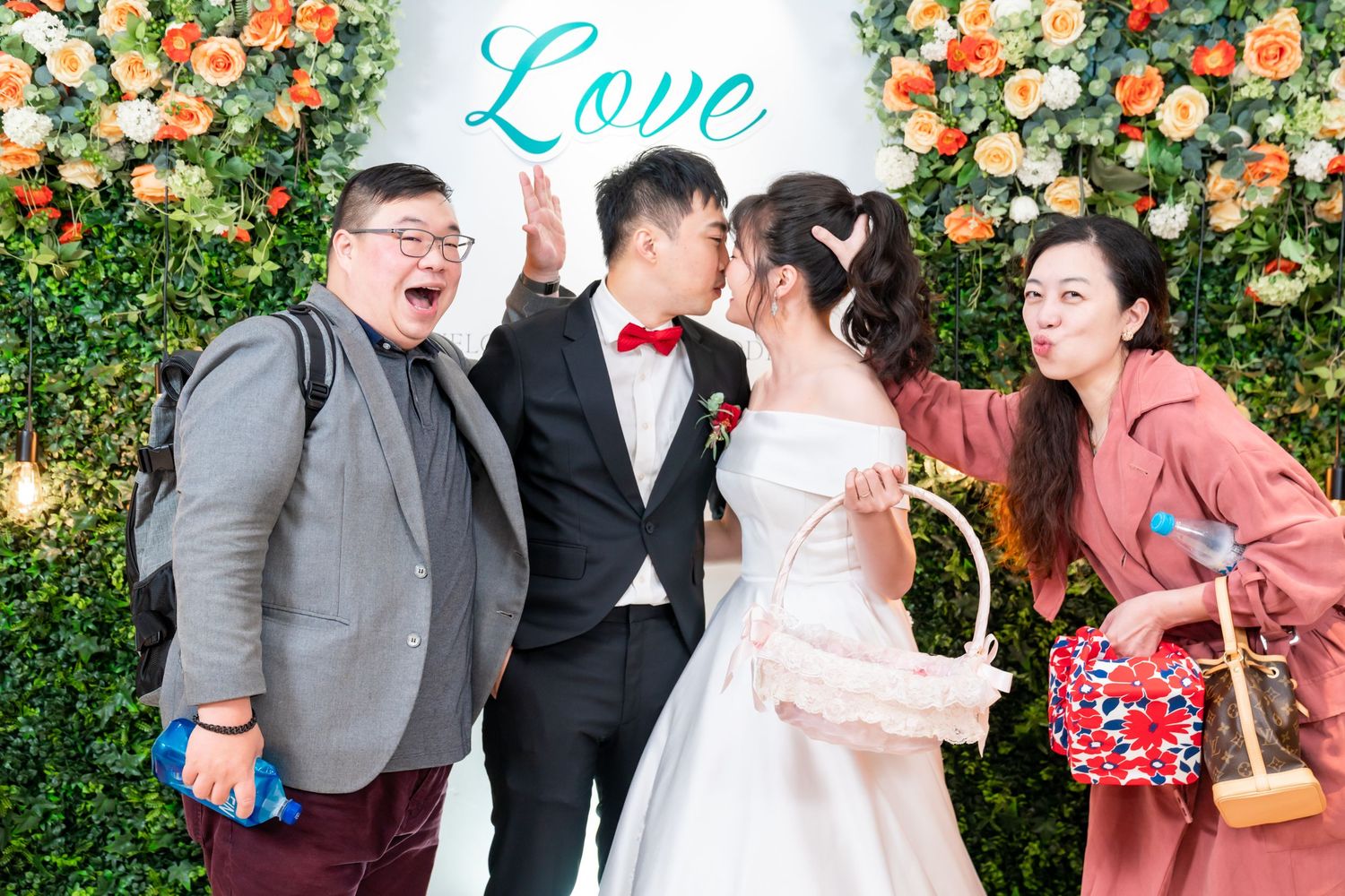 Wedding party shares a candid moment of laughter in front of floral backdrop.