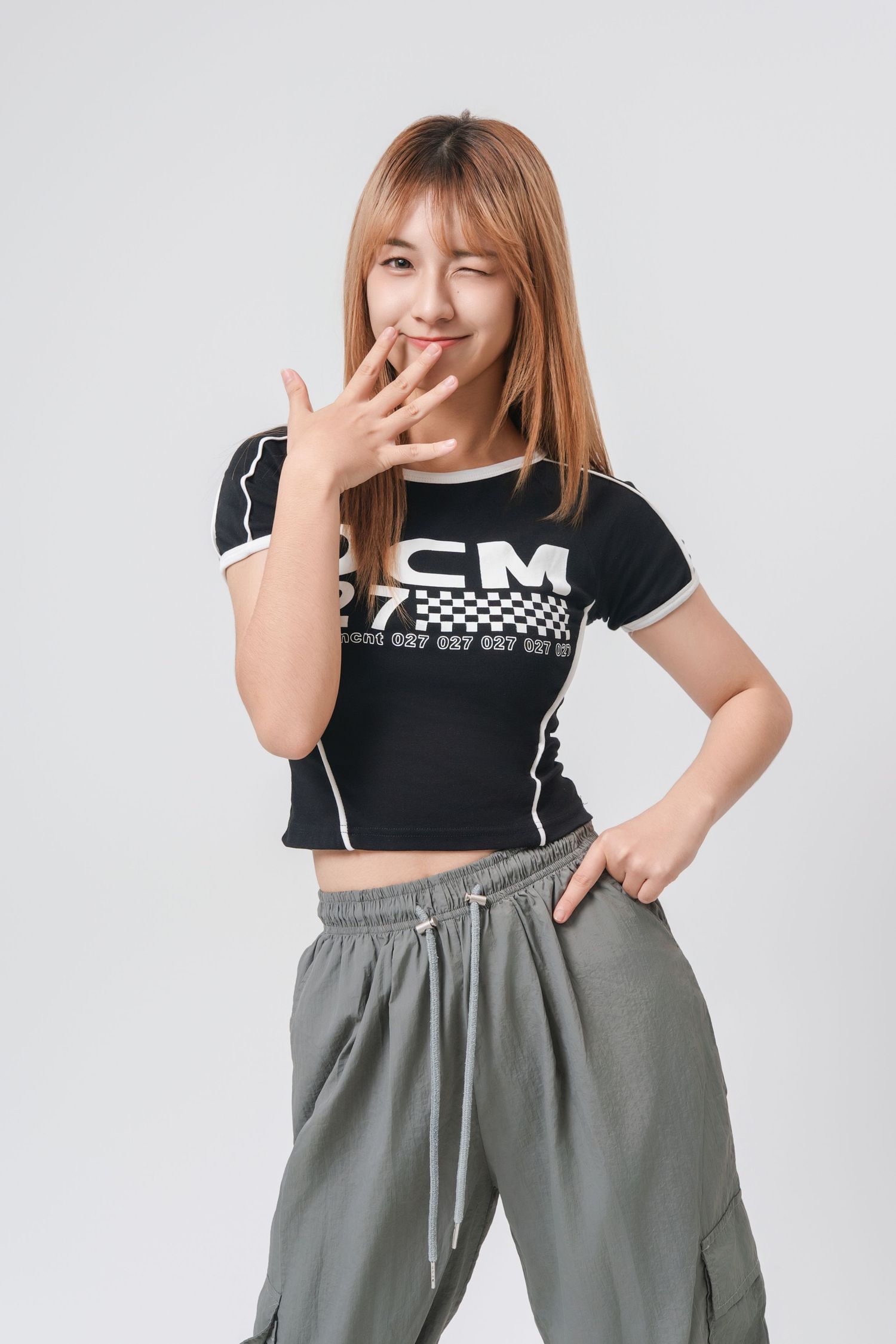 Person in black crop top and gray cargo pants poses playfully in three different stances against white background.
