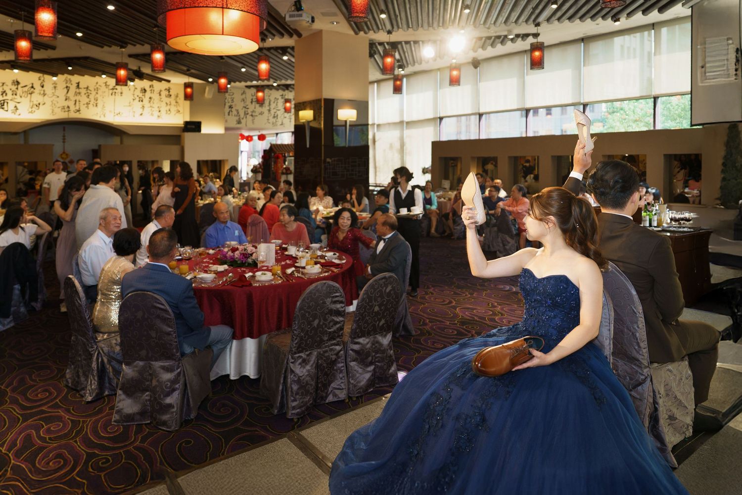 People gather in a dimly lit restaurant dining room with red accents and modern decor for a social event.
