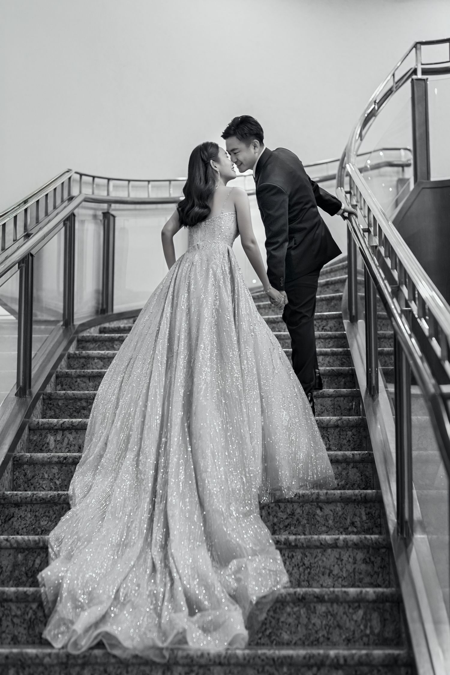 A romantic black and white photo sequence of a couple kissing on elegant marble stairs in formal wedding attire.