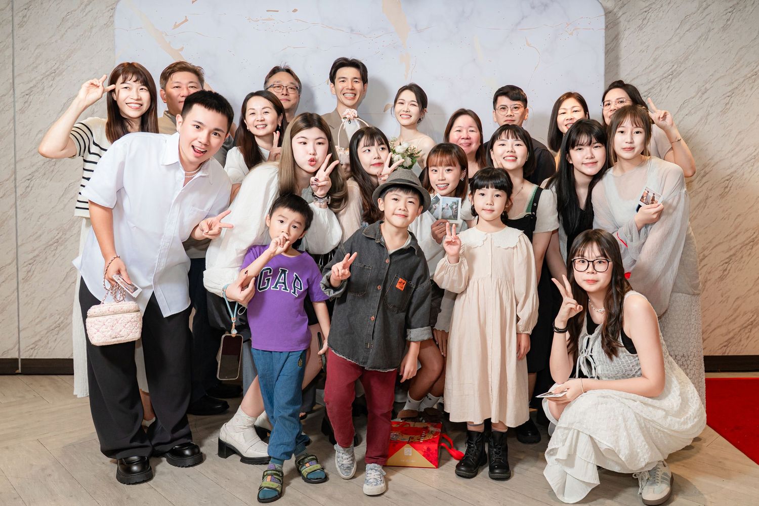 A joyful group of young people pose together at an event, expressing excitement with energetic gestures and smiles.