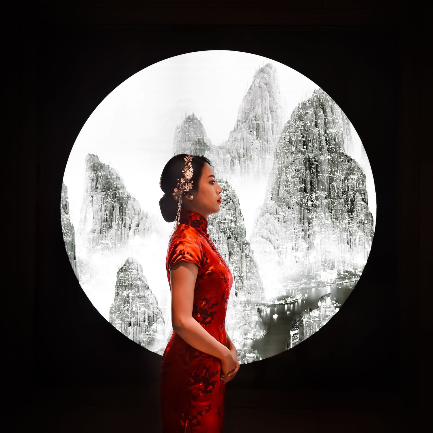 A woman in a red qipao dress poses against a circular backdrop with traditional mountain landscape art.