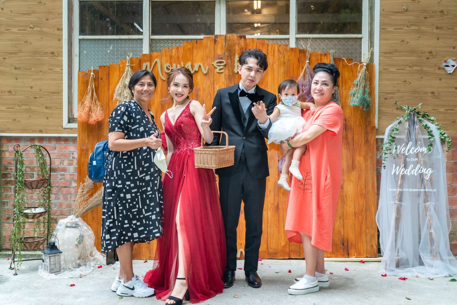 A family gathering with mixed attire poses in front of an orange backdrop with decorative elements.