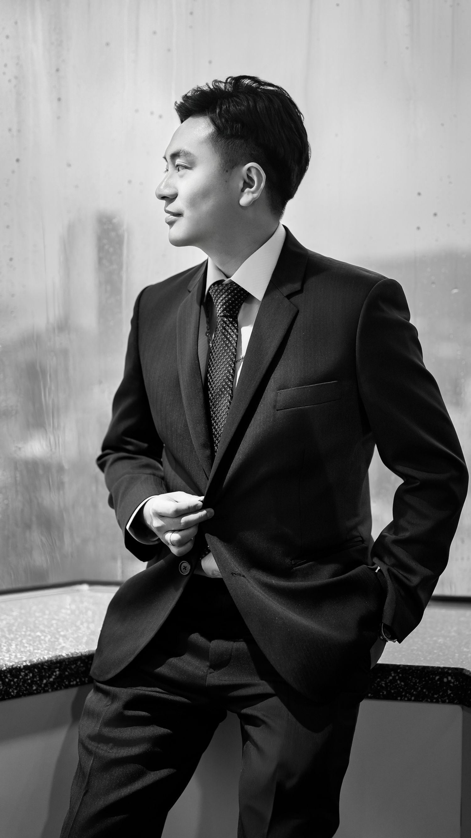 Black and white portrait series showing a person in a business suit posing against a minimalist background.