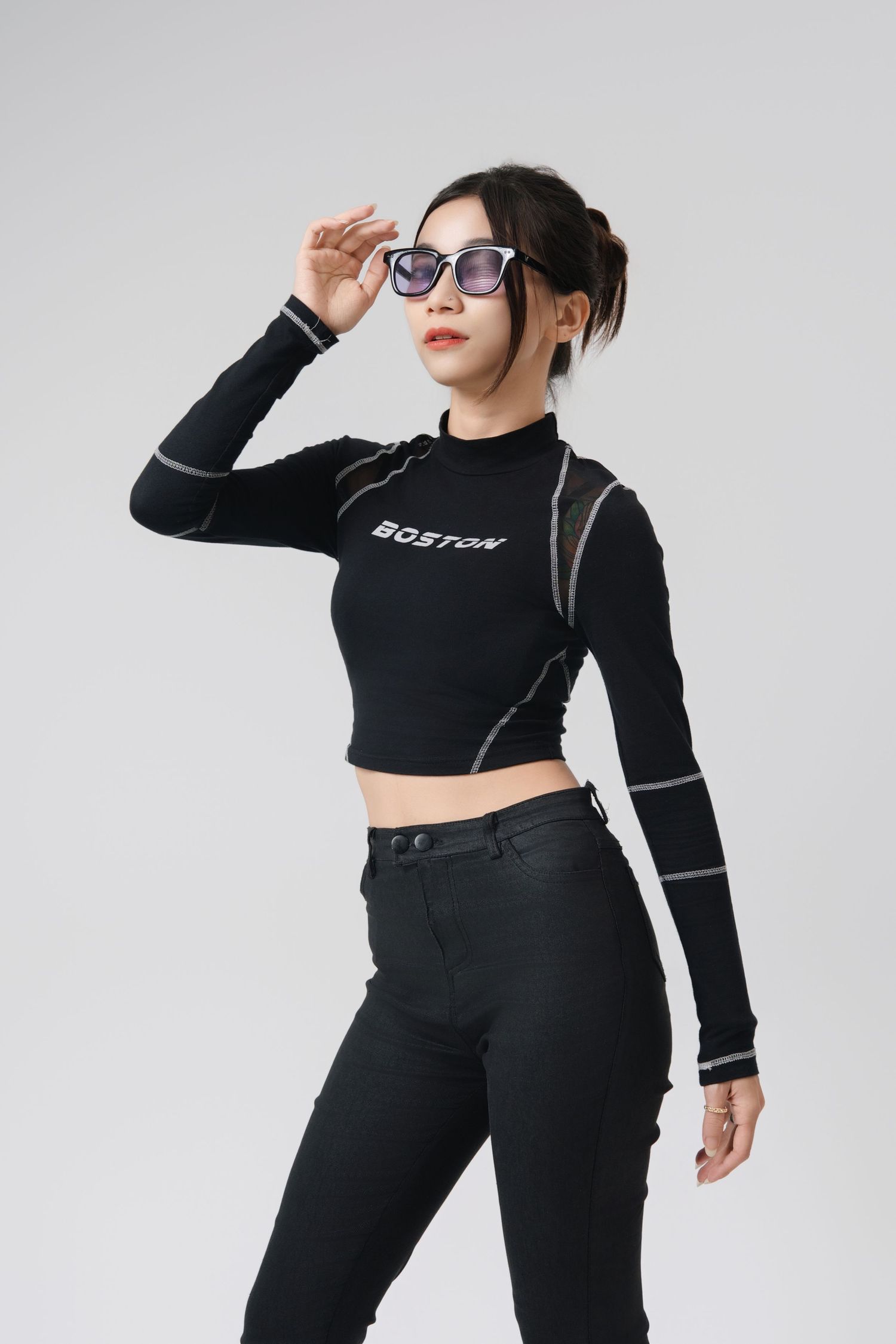 Model in all-black athleisure outfit with crop top and pants poses against white background in dynamic poses.