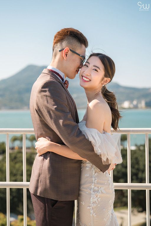 Romantic couple shares intimate moment on balcony overlooking ocean view.