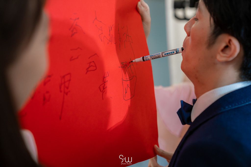 Groom writing on red paper during traditional Chinese wedding customs.