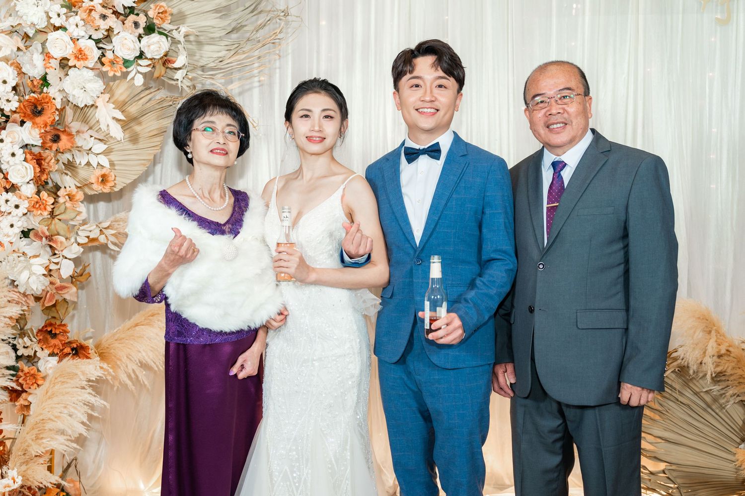 Wedding celebration scene with floral arch decorations, formal attire, and champagne against an elegant beige backdrop.