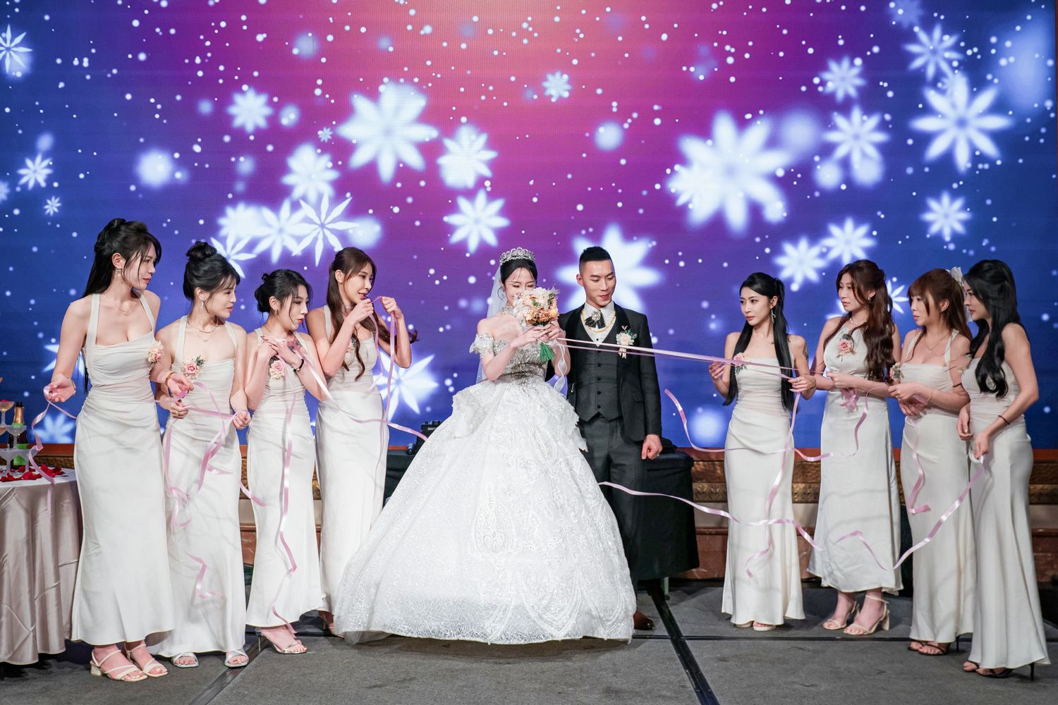 Wedding party poses together against a magical backdrop of glowing snowflakes and purple-blue lighting effects.
