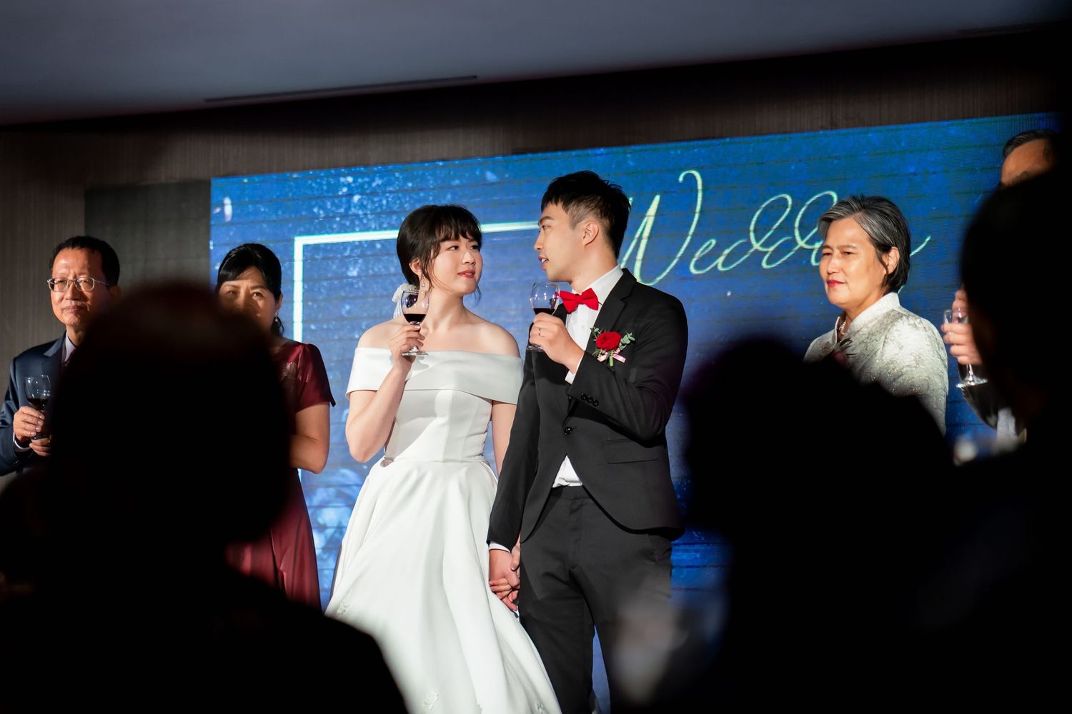 A wedding couple shares a moment on stage with blue lighting and decorations.