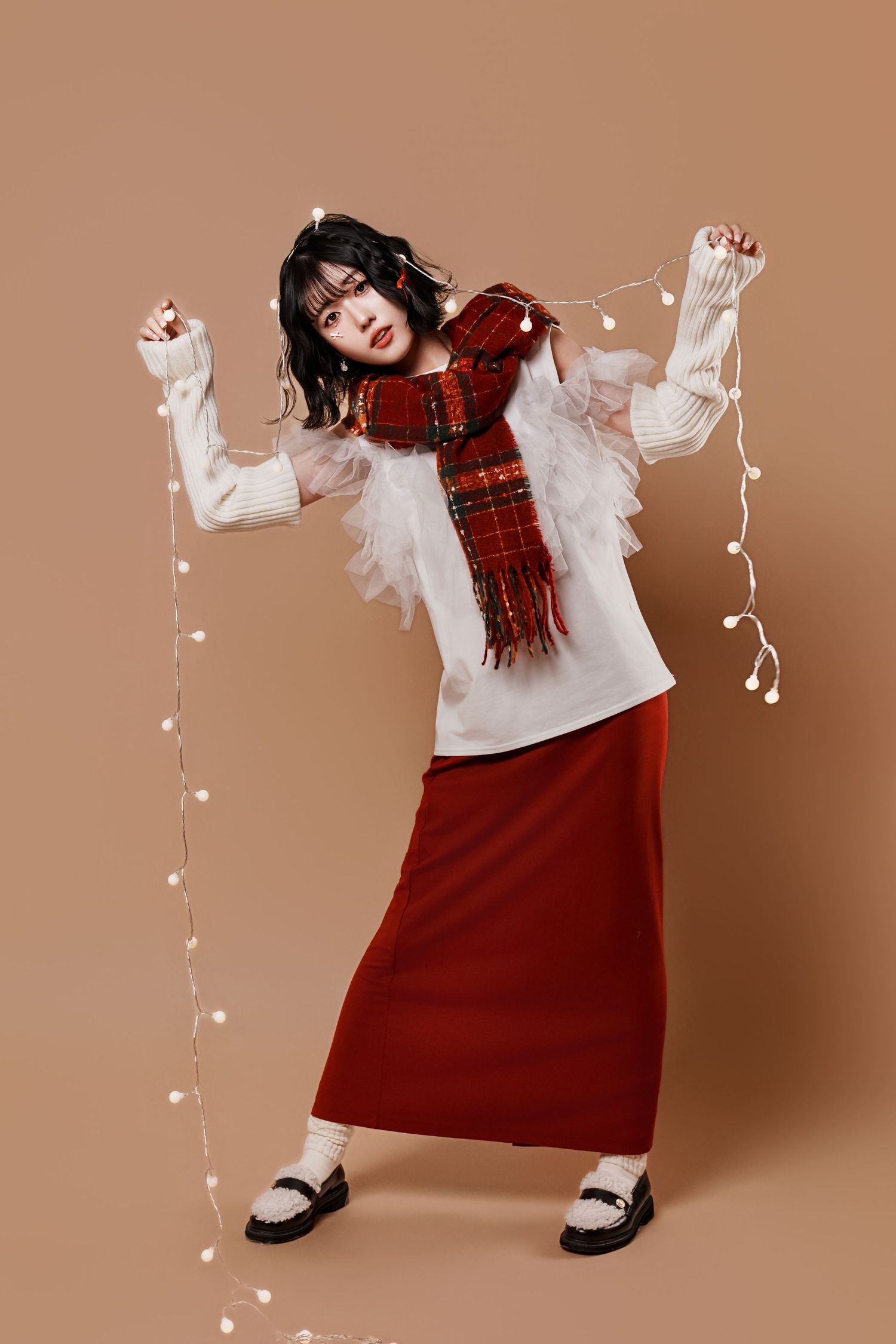 A sequence of four fashion photos showing a red plaid winter outfit with white ruffled sleeves against a brown backdrop.