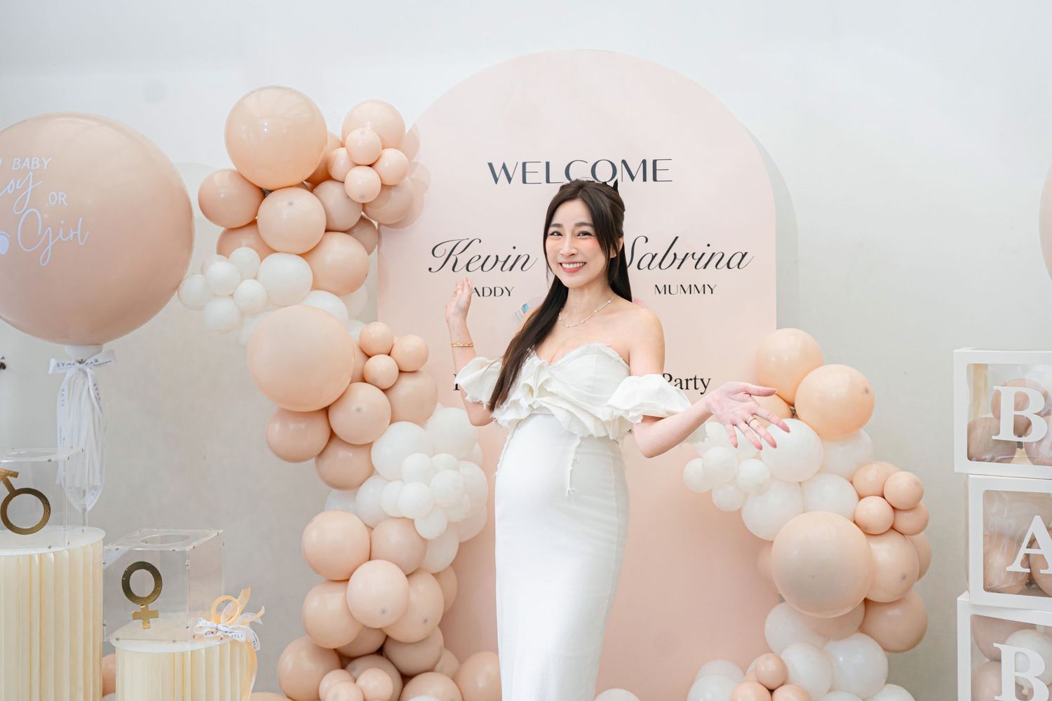 Elegant event space decorated with blush pink balloon garlands and welcome sign in soft neutral tones.