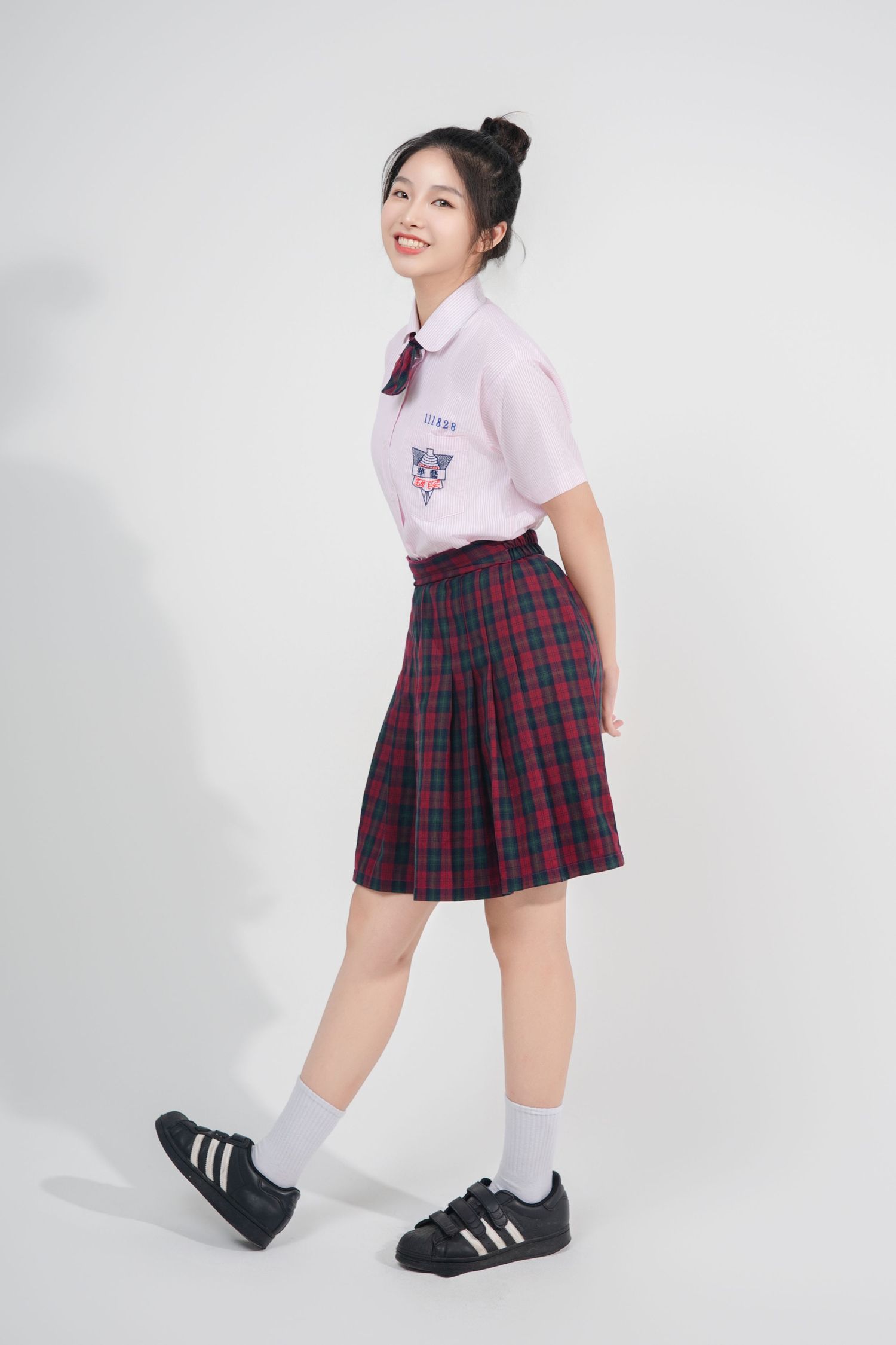 A student wearing a pink polo shirt and plaid skirt poses in different angles against a white background.