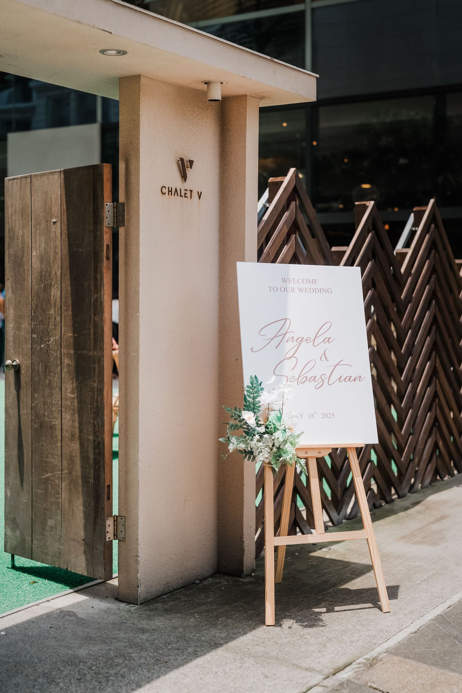 Wedding venue entrance with rustic wooden lattice panels and elegant welcome signage displayed on easels.