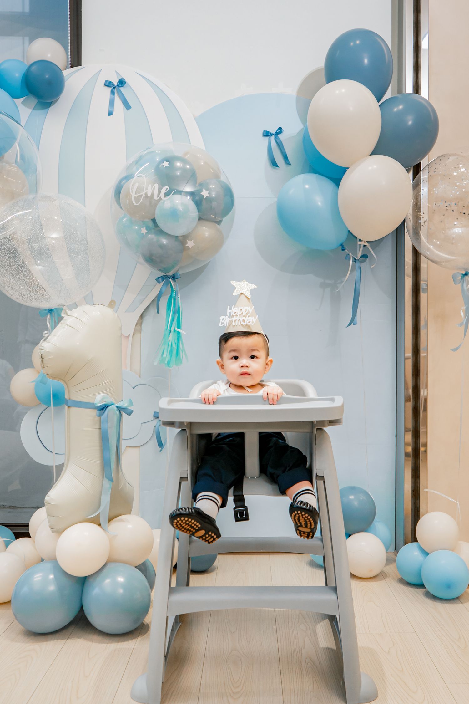 Blue and white balloons decorate a bright room with wooden floors for a festive celebration.