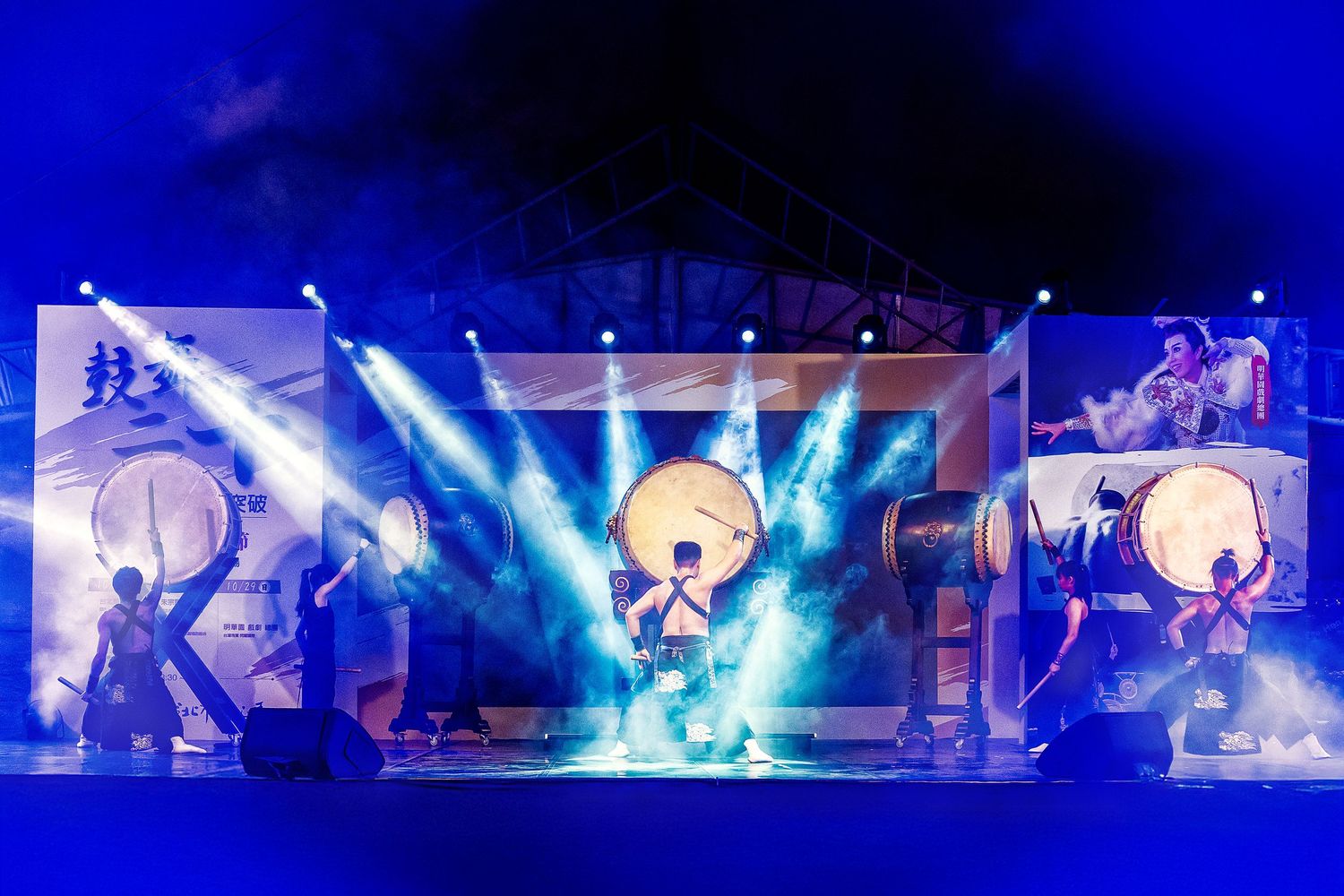 Concert stage illuminated with vibrant blue lights and fog effects during a live performance.
