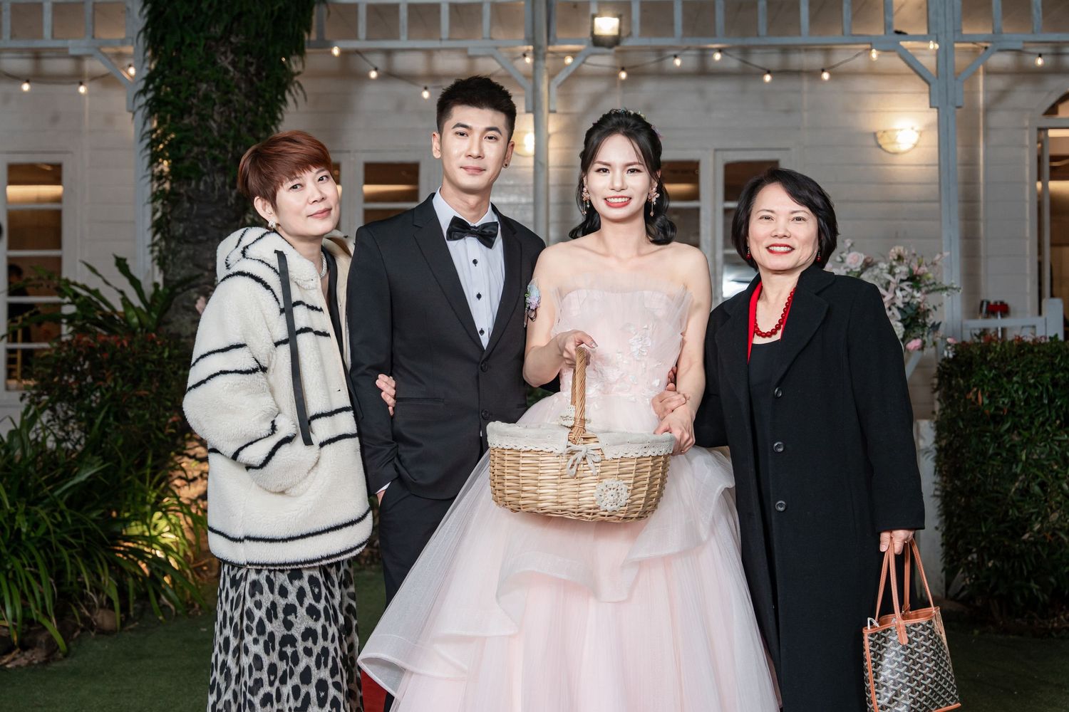 A group of formally dressed people pose together at an elegant wedding reception venue.