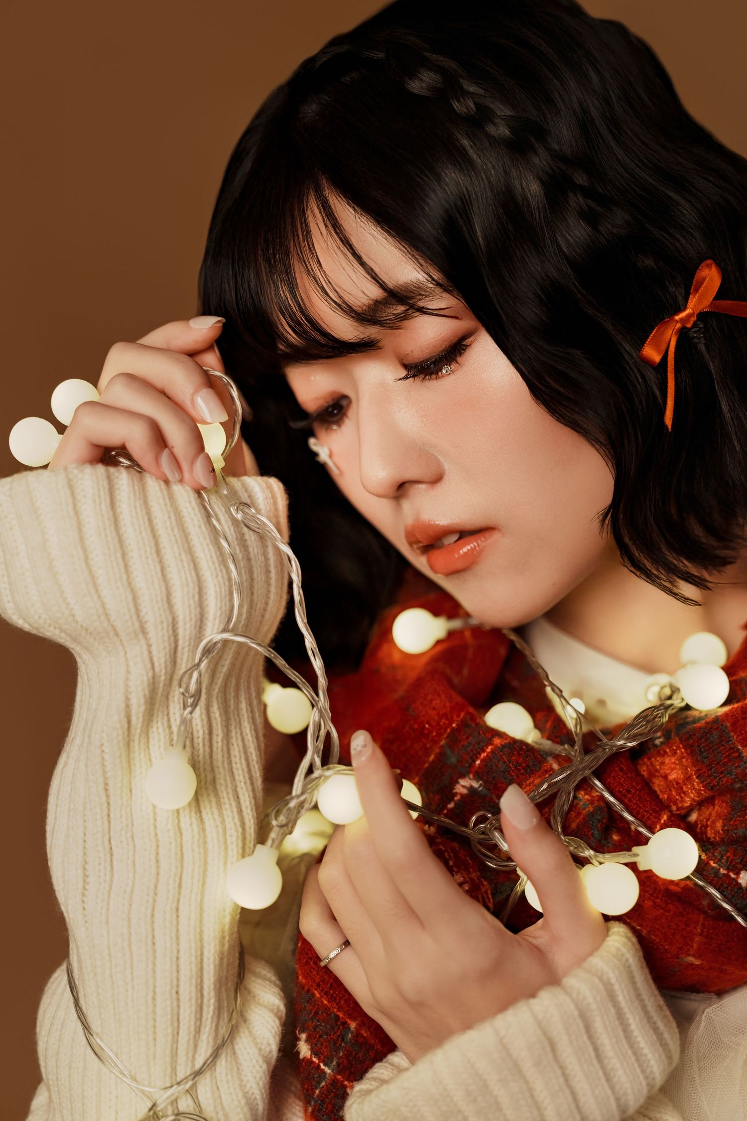 A dreamy portrait with string lights and a red violin against a cream sweater creating a cozy artistic mood.