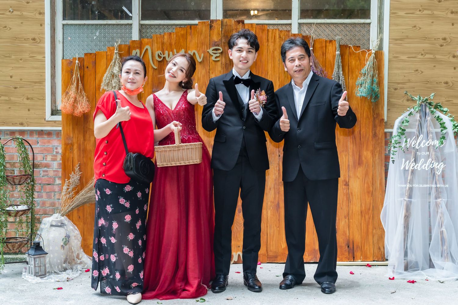 Small group in formal wear shows peace signs while posing against wooden backdrop.
