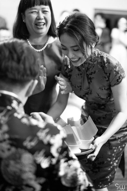 A black and white photo captures joyful laughter during a traditional tea ceremony.