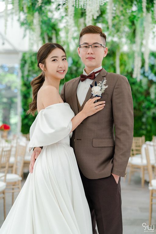 Elegant wedding portrait in venue with hanging greenery and white decor.