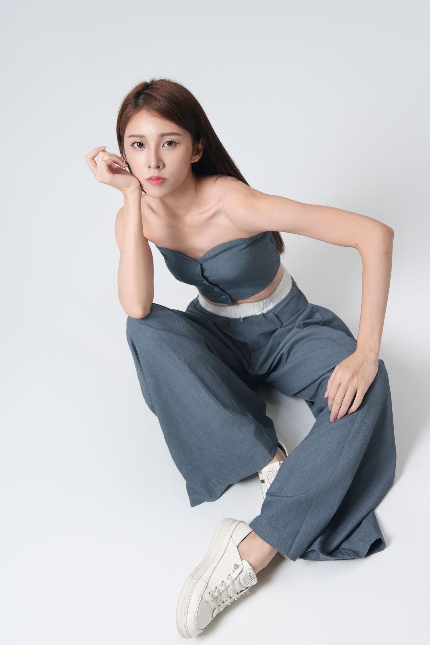 Model in gray loungewear poses gracefully on white background showing casual athleisure style in fashion photoshoot.