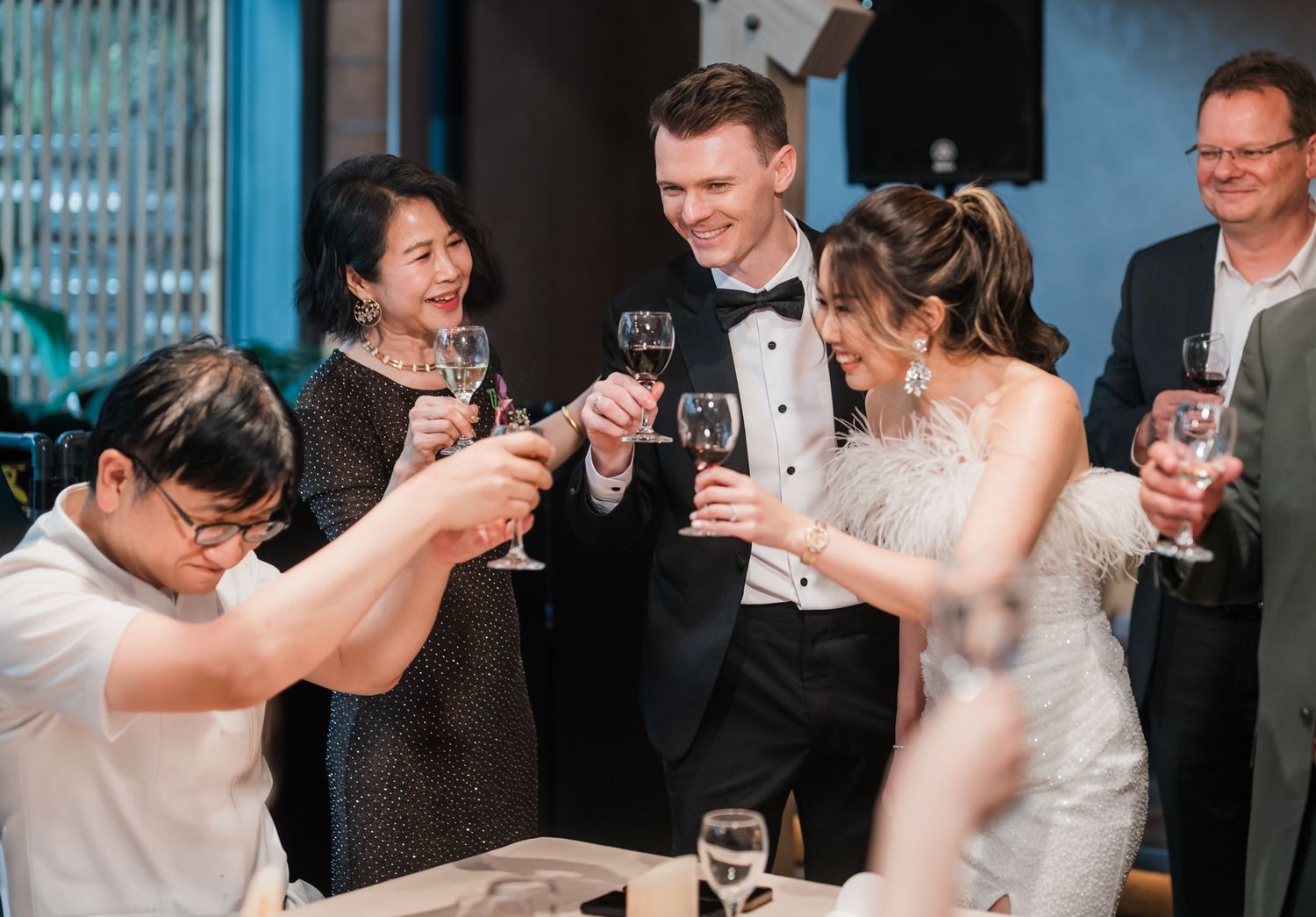 Wedding party guests raising champagne glasses in celebration at an elegant indoor reception.