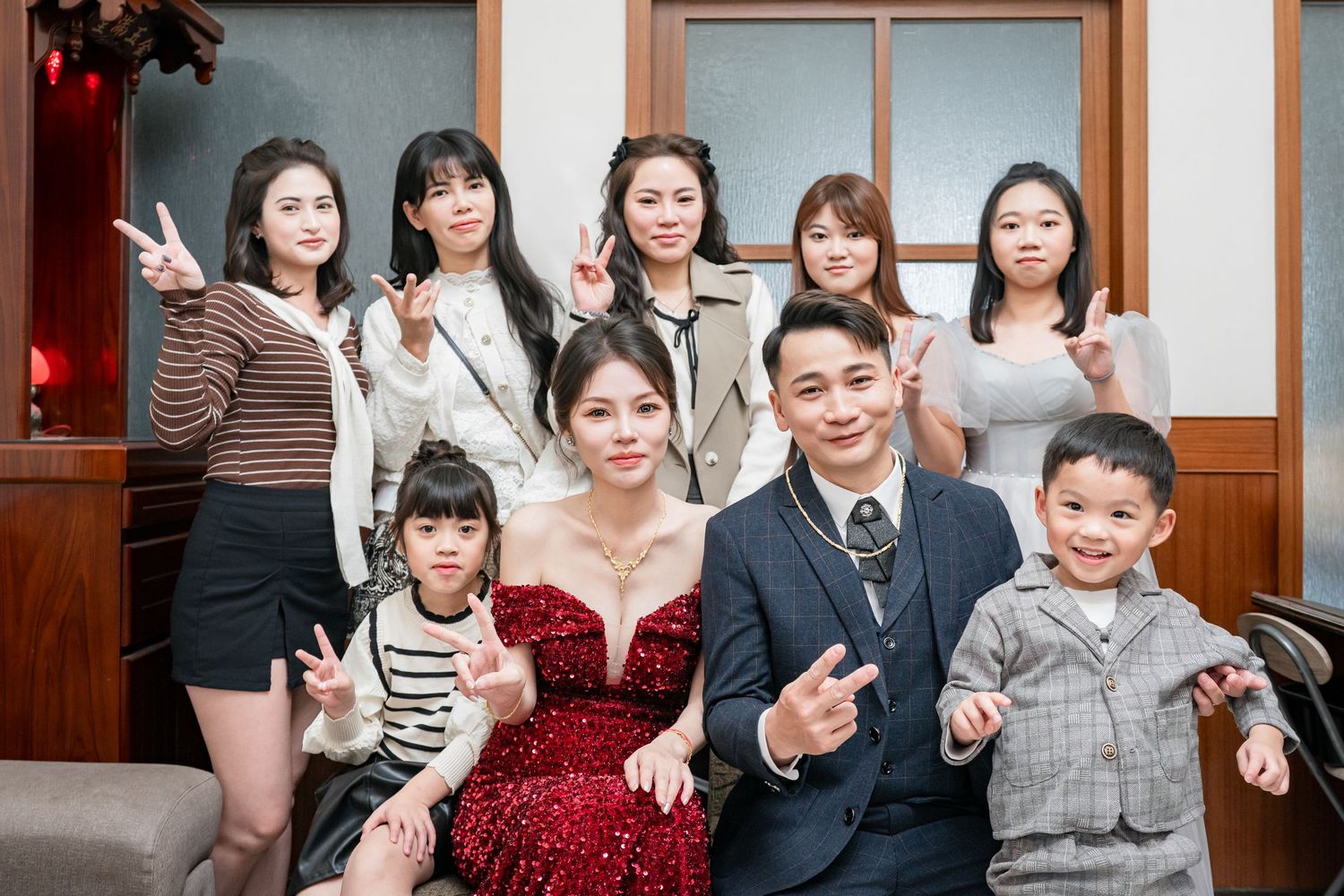 A group of people gather together at a social event wearing formal attire and posing for photos.