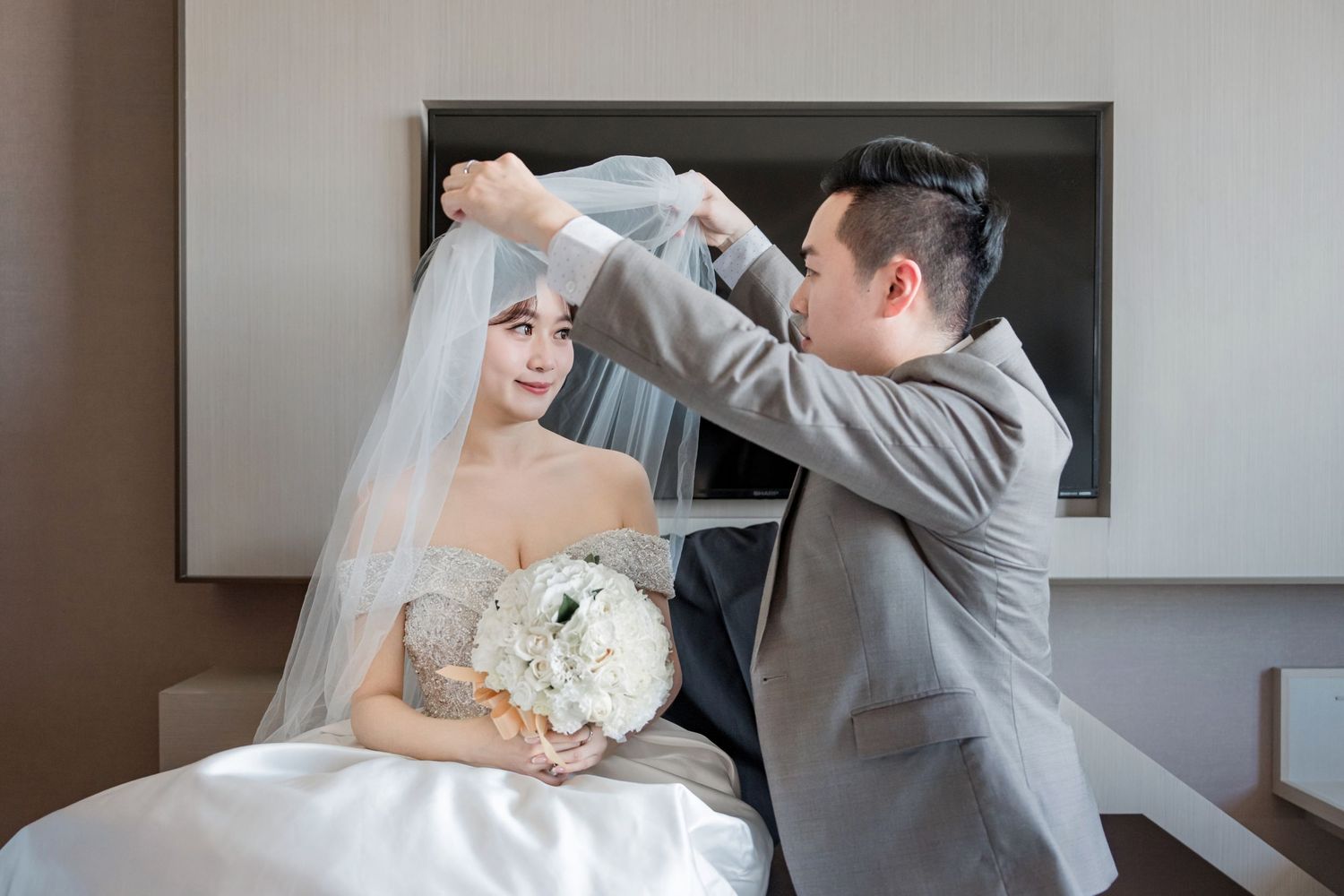 A wedding couple shares a tender moment during their first look in an elegant indoor setting.