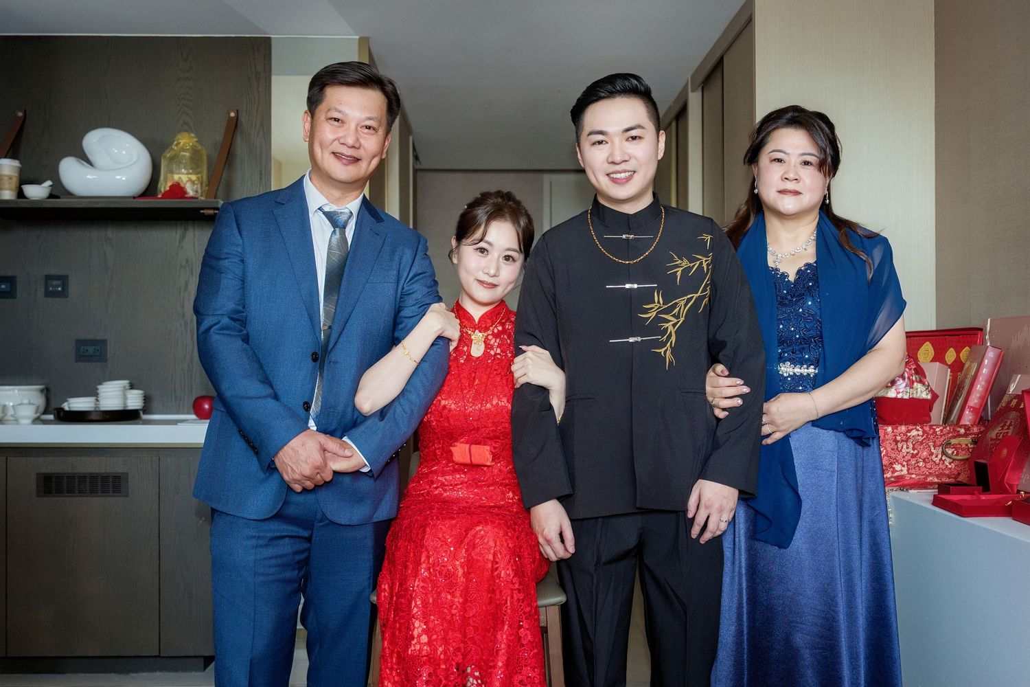 Group photo showing people in formal attire including blue suits and a vibrant red dress at a special occasion.