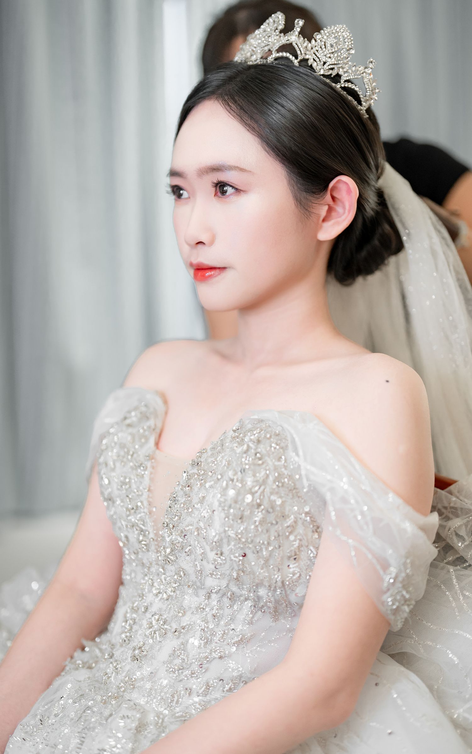 A bride in an elegant white wedding gown with crystal embellishments and a delicate tiara poses for bridal portraits.