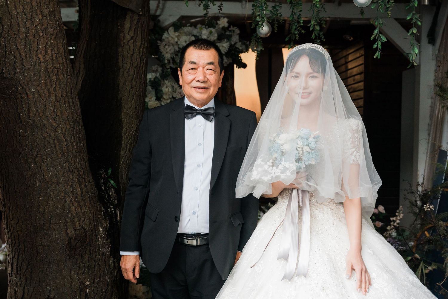 A bride and groom pose together in formal wedding attire during their ceremony.